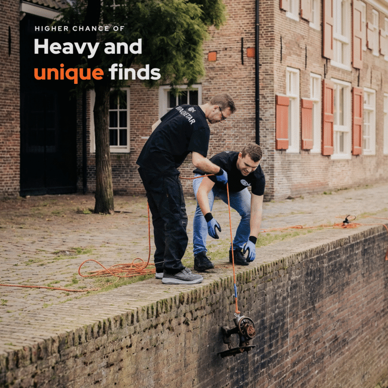 Magnetar lifestyle fishing magnet photo showing two men pulling a heavy, unique vintage sewing machine find out of an urban canal.